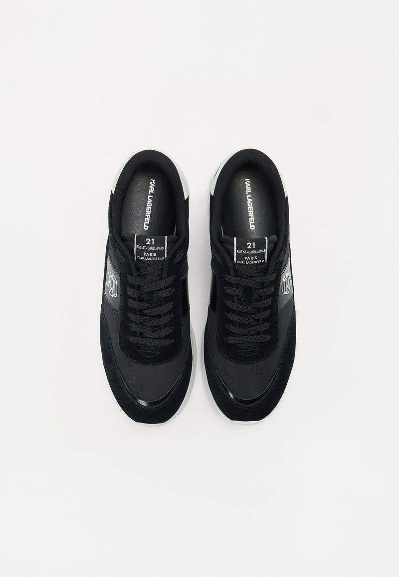 Baskets noires en cuir et suède, avec un bout rond, un laçage et un accent logo sur le côté. Semelle blanche.