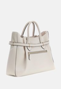 Beżowa torba typu tote wykonana ze skóry, z podwójnymi uchwytami, złotymi dodatkami, przednią kieszenią na zamek oraz kontrastującym czarnym obszyciem na krawędziach. Teksturowana powierzchnia.