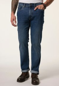 Dark blue denim jeans with a straight-fit design, five pockets, and rolled-up cuffs. Worn with brown leather lace-up boots.
