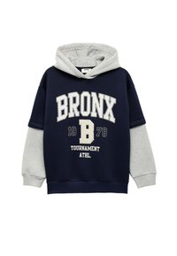 Mörkblå och grå hoodie med känguruficka, prydd med "BRONX 1978" i stora vita bokstäver och grå ärmar. Blandat bomullstyg.