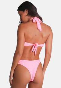 Rosa bikini med halterneck-design. Toppen har knytning, och botten har en högskuren stil som betonar det släta, elastiska tyget.