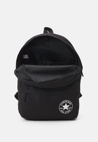 Schwarzer Canvas-Rucksack mit abgerundetem oberen Teil, Reißverschluss und Fronttasche. Verfügt über ein weißes Chuck Taylor All Star Logo-Patch.
