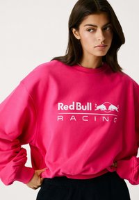 Sudadera rosa hecha de una mezcla de algodón, con un gran logo blanco de "Red Bull Racing". Corte oversize con puños y cuello de canalé.