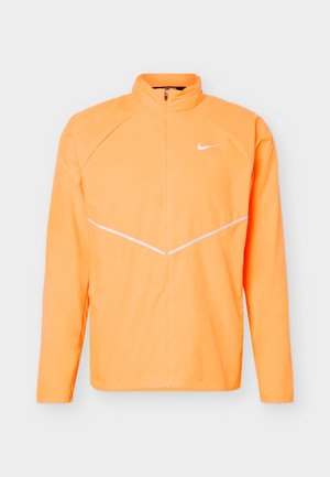 Bright orange full-zip athletic jacket with stand-up collar, long sleeves, white Nike swoosh logo on chest, and subtle diagonal white lines.