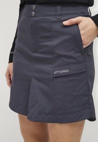 Marineblauwe knie-lange rok van ademende stof, met een platte tailleband, twee knopen, zijzakken en geborduurd logo-detail.