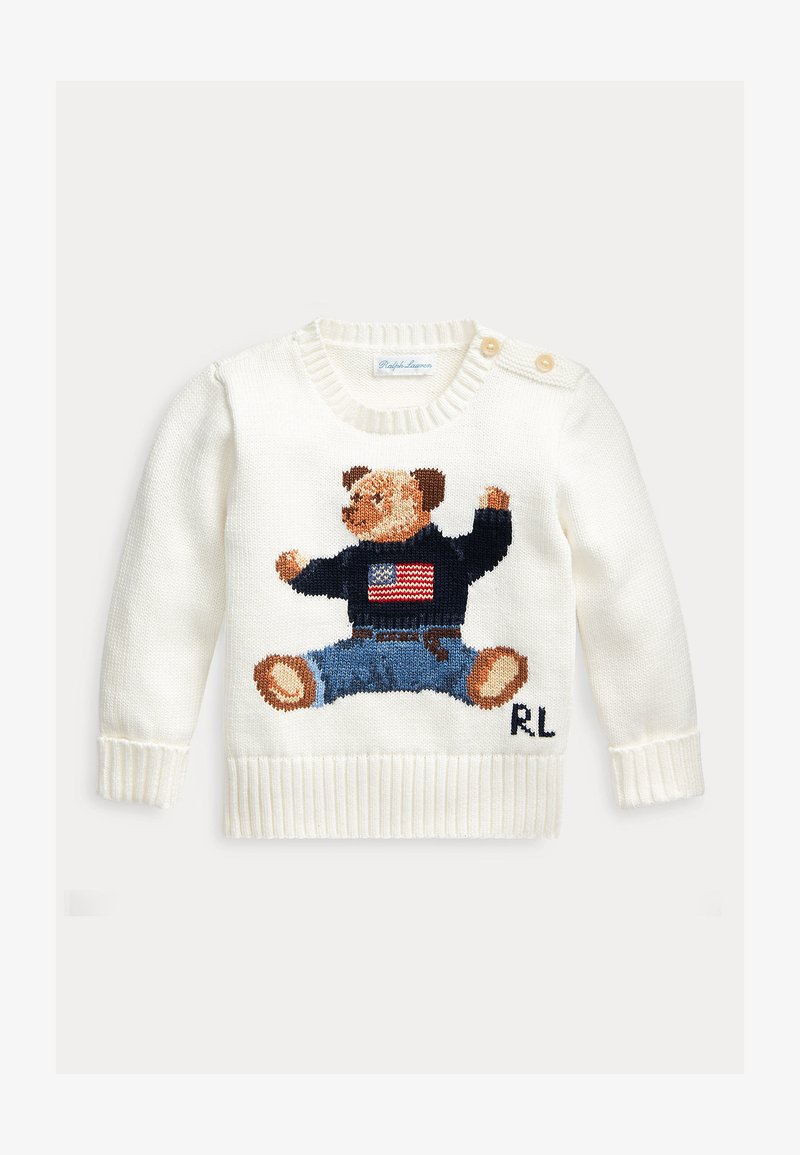 Pull enfant blanc en maille avec un ours portant un pull sombre avec un drapeau américain et un jean bleu, poignets et ourlet côtelés, deux boutons aux épaules.