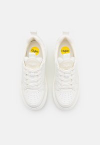 Fehér sneaker perforált orrpánttal, lapos fűzőkkel és párnázott bokarésszel. Jellemzője a nyelvén található kör alakú logo és a sárga talpbetét.