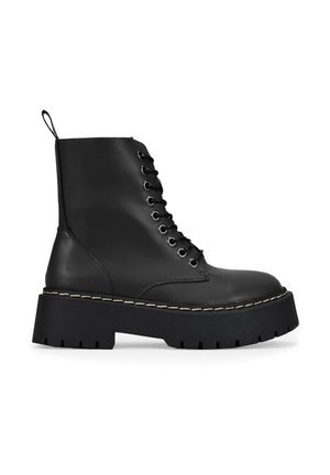 Bottines en cuir noir à bout rond, à lacets sur le devant et semelle épaisse. Présente une couture contrastante le long de la semelle.