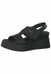 Black wedge sandals featuring a wide strap with cut-out design and adjustable buckle. Smooth synthetic material, open toe, and rounded sole.