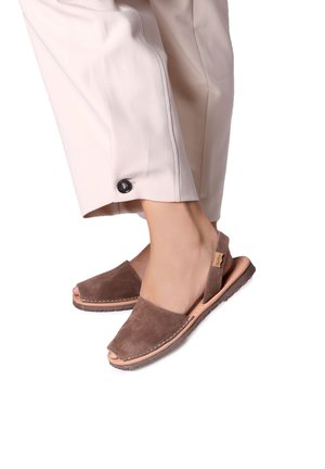 Bruine suede sandalen met een open teen en een slingback riem. Kenmerken zijn een gestikte accent op de zool en een textuur op de outsole voor grip.