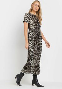 Vestido midi de estampado de leopardo con mangas cortas, cintura fruncida y una falda fluida. Combinado con botas negras hasta el tobillo.