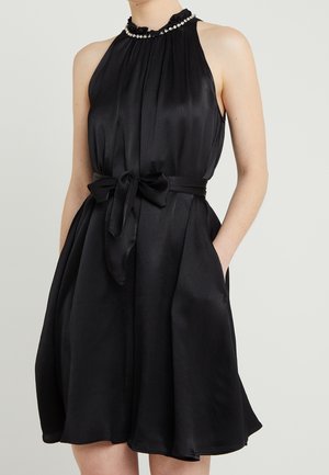 Robe sans manches en satin noir avec un col haut plissé, des embellissements en perles, une ceinture nouée à la taille et des poches latérales.