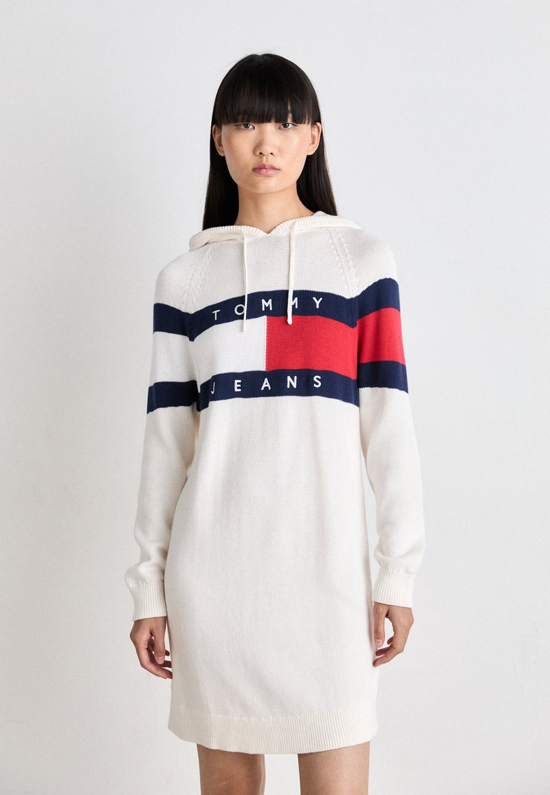 Abito felpa color crema con strisce orizzontali blu navy e rosse, caratterizzato dal logo "TOMMY JEANS", polsini a coste e cappuccio regolabile con cordino.