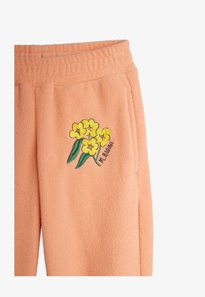 Peach fleece pants featuring a floral embroidery design with yellow flowers and green leaves. Elastic waistband with side pockets.