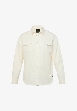 Langærmet skjorte i cremefarvet stof med knaplukning foran, to brystlommer, trykknapper og en let buet nederkant.