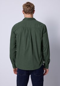 Camisa verde de manga larga con un sutil patrón texturizado, que cuenta con un cuello con botón, espalda plisada y puños con botón.