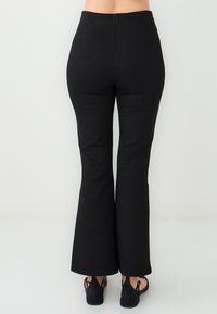 Zwarte flared broeken met een hoge taille, gemaakt van een rekbare stof, met een gladde textuur en een nette naad aan de achterzijde.