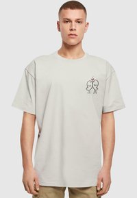 Lys grå oversized t-shirt i blød bomuld, der har et lille sort tegneserie-design af to fugle med et hjerte på venstre brystområde.