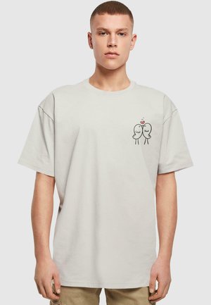 Lys grå oversized t-shirt i blød bomuld, der har et lille sort tegneserie-design af to fugle med et hjerte på venstre brystområde.