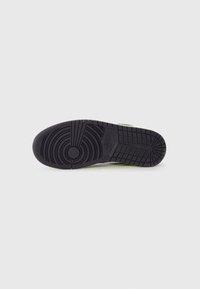 Zwarte rubberen sneakerzool met een textuurpatroon voor grip, cirkelvormige en rechthoekige vormen, met een logo dat aan de zijkant is ingebed.