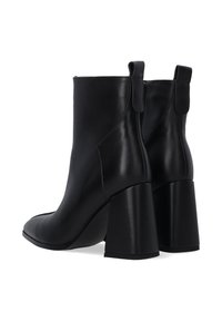 Czarne skórzane botki za kostkę z wydłużonym noskiem i masywnym obcasem. Posiadają małe pętelki z tyłu oraz gładką powierzchnię.