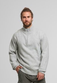 Lichtgrijze kwart-rits pullover trui met ribbelkraag en -zoom, gemaakt van gestructureerde stof. Bevat lange mouwen en een ontspannen pasvorm.