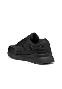 Svart lågtopp sneakers med vadderad krage, sydd paneldesign och tjock sula, visad i en bakre 3/4 vinkel mot vit bakgrund.