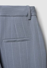 Pantaloni grigi a righe con vita alta, passanti per cintura e una tasca posteriore singola con patta arrotondata. Tessuto con una consistenza liscia.