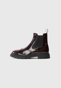 Stivali Chelsea in pelle verniciata bordeaux con pannelli elastici laterali, dettagli brogue e suola in gomma nera. Presentano una linguetta per facilitare la calzata.
