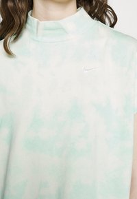 Light green tie-dye sleeveless top with a high neck and a small, embossed white Nike logo on the chest, made from soft cotton material.