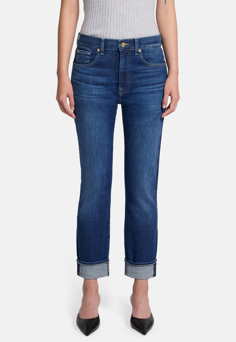 Jeans denim w ciemnoniebieskim kolorze o prostym kroju, z podwiniętymi mankietami, pięcioma kieszeniami i zapięciem na guzik. Gładka tekstura bez wzorów.