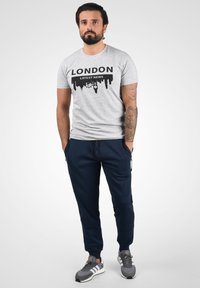 Gray cotton t-shirt with black "LONDON LATEST NEWS" graphic; navy jogger pants with elastic waistband; gray sneakers with white soles.