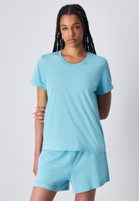 Maglietta in cotone azzurra chiara con maniche corte arrotolate, scollatura rotonda e vestibilità comoda, abbinata a pantaloni corti blu coordinati.