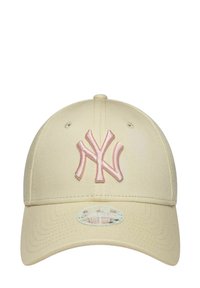 Gorra beige de los New York Yankees con logotipo bordado en rosa claro, visera curva, ojales para ventilación y un botón redondo en la parte superior.