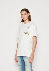 Camiseta de algodón blanca con un gráfico de un personaje de dibujos animados con los brazos en alto, acompañado del texto "Los Simpson" en amarillo.