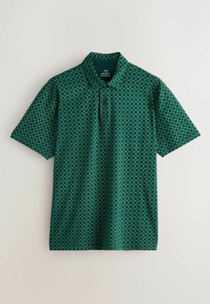 Camisa polo verde con un patrón geométrico, que cuenta con un collar, dos botones y mangas cortas; hecha de una tela suave.