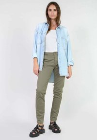 Light blue denim shirt, white tank top, olive green pants, and black strappy sandals. The shirt has a relaxed fit and long sleeves.