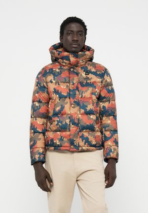 Veste camouflage rembourrée avec un col haut, présentant un mélange de couleurs orange, bleu et beige, des boutons-pression, et une texture lisse et brillante.
