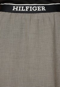 Schwarz-weiße karierte Boxershorts mit einem markierten schwarzen Bund, auf dem "HILFIGER" in weißer Schrift steht. Weicher Baumwollstoff.