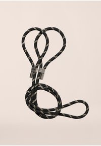 Μαύρο και λευκό πουά κορδόνι με μεταλλικά εξαρτήματα, που διαθέτει πλεκτή υφή και βρόχους, ασφαλισμένο στη μέση με ένα μεταλλικό κούμπωμα.