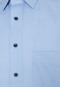 Camicia a scacchi azzurro chiaro con bottoni neri e una tasca sul petto con un piccolo logo ricamato.