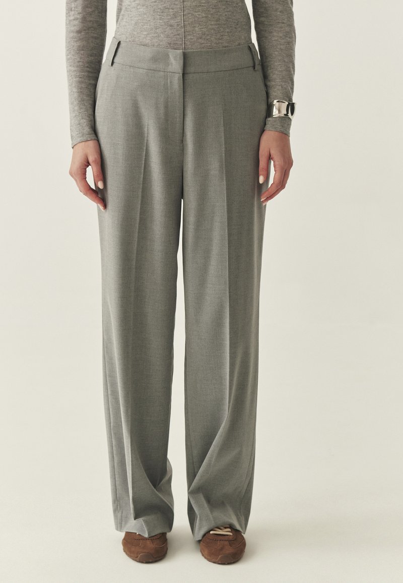 Szare spodnie o szerokich nogawkach wykonane z miękkiej, teksturowanej tkaniny, z przednim kantem, kieszeniami po bokach i dopasowaniem w talii.