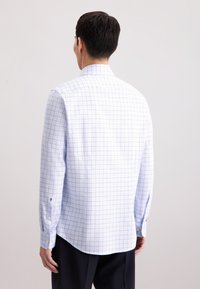 Camicia a maniche lunghe di colore azzurro chiaro con un motivo a griglia bianca, dotata di colletto a punta e polsini abbottonati. Tessuto liscio con una leggera lucentezza.