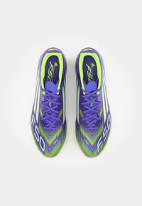 Paarse en groene voetbalschoenen met een patroon op de bovenkant, voorzien van strepen, een ronde neus en paarse veters. Er staat "F50" op de zijkant.