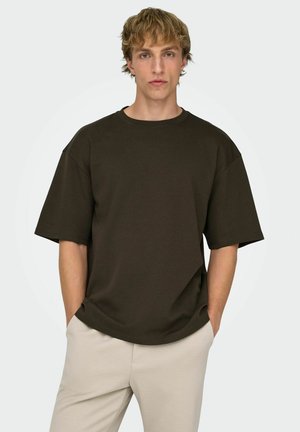 Ciemnobrązowa, oversize'owa koszulka z krótkim rękawem, okrągłym dekoltem i miękką fakturą, zestawiona z jasnobeżowymi spodniami; casualowy krój.