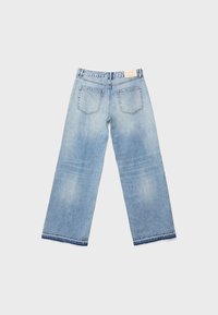 Jean en denim bleu clair vu de dos avec deux poches arrière et une petite étiquette de marque beige sur la ceinture.