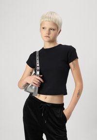 Melnā īsā t-kreklā ar īsām piedurknēm, kopā ar melnajām samta biksēm. Tur mazu sudraba somiņu ar rakstainu siksnu.