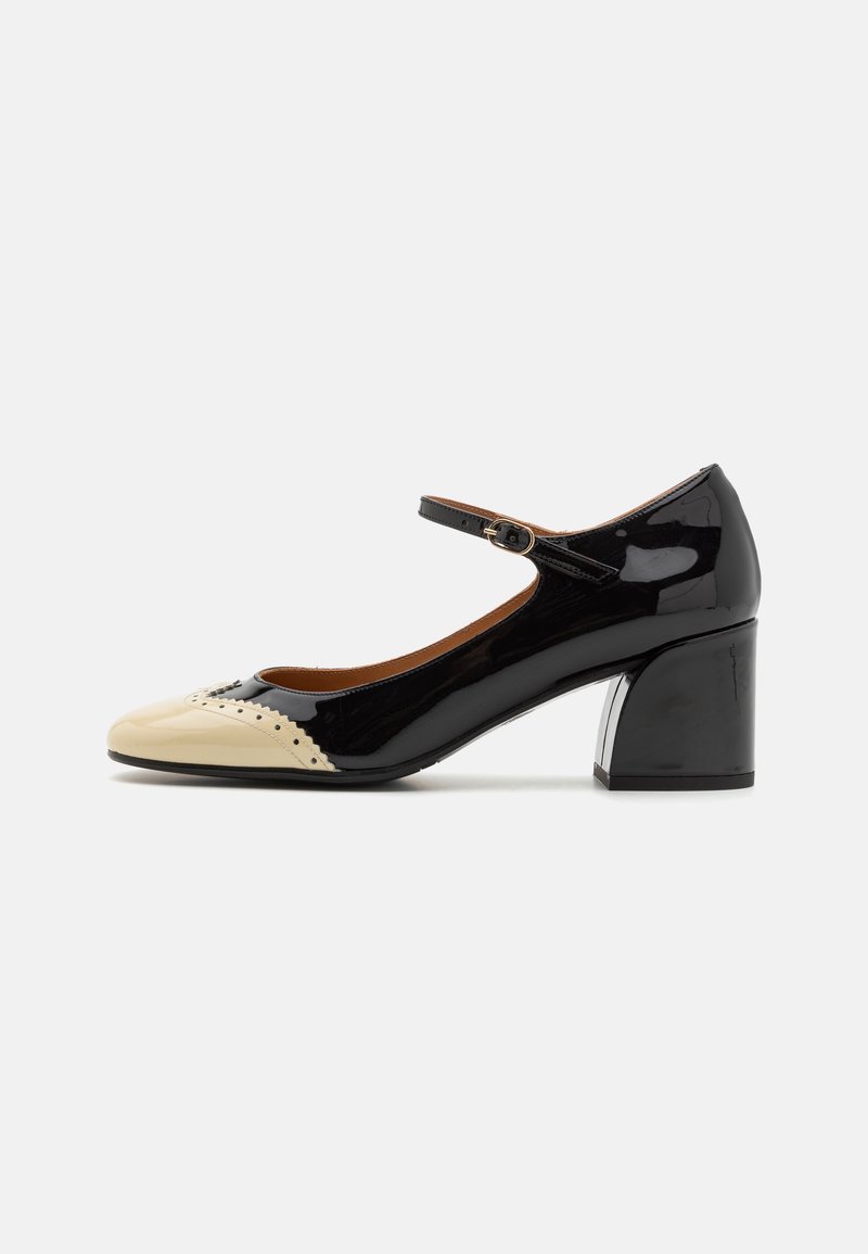 Chaussure Mary Jane en cuir verni noir avec bout texturé beige, petit talon carré et bride de cheville réglable avec boucle.
