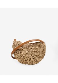 Bolso de paja trenzada en forma circular, con una correa de cuero en tono marrón y un intrincado detalle de nudos en toda la superficie.