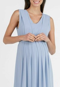 Ljusblå gravidklänning med V-hals, korta ärmar och plisserad design. Tillverkad av mjukt tyg, har den en flödande, avslappnad passform.
